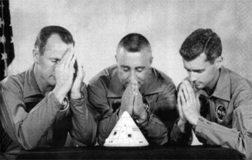 The crew of Apollo 1 praying over a model of their command module.